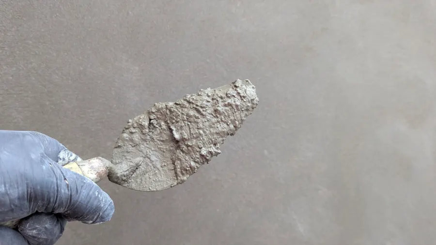 Spaan tegen een strak gestuukte wand
